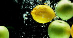 Fruit, water and citrus with vitamin c for fresh produce, hydration or wash on a black background. Closeup of natural organic apple, lemon or nutrition for citric acid in splash for healthy diet