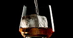 Glass, whiskey and ice with alcohol, pour and bourbon on black studio background. Empty, cold and smooth drink with refreshment, cognac and cube with scotch, luxury and liquor with closeup and brandy