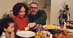 Food, happy family and serving dinner for thanksgiving celebration in home at night. Child, mom and dad share meal, corn or eating healthy vegetables in plate with interracial people bonding together