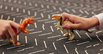 Children, hands and play with dinosaur in home for fun activity, imagination and creative learning with growth or development. Animal or reptile toys, closeup and ground in house for entertainment.