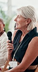 Senior woman, microphone and audience at conference for smile, question and agenda for info, training or development. Person, speaker and audio in meeting at tradeshow, workshop or global convention