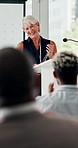 Mature woman, podium and audience with applause for award, announcement or thank you at seminar. Senior female person or speaker in gratitude to crowd clapping for meeting, winner or achievement