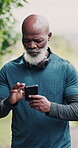 Senior, black man and phone in nature for fitness, choose music and navigation app for running. Male athlete, mobile and outdoor exercise with progress report, performance assessment and tracking