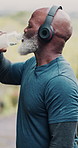 Senior, black man and drinking water for fitness with outdoor exercise, headphones and body detox. African person, thirsty and liquid nutrition for hydration with music sound, playlist and nature run