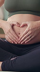 Woman, pregnant and heart hands in home for yoga, love and care for unborn baby. IVF healthcare, future mom and holding abdomen in pilates class for fitness, healthy body and childcare in living room