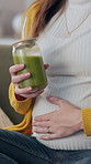 Pregnant woman, drinking juice and relax in home, hands and prenatal vitamin for immune system. Female person, green smoothie and nutrition for maternity care, touching belly and glass of minerals