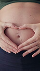 Woman, pregnant and heart hands on stomach for love, future and care for unborn baby at home. Fertility, maternity leave and closeup of belly with gesture, security and support by holding tummy