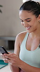 Cellphone, woman and smile for message, yoga and relax on mat in gym, online and happy for communication. Health club, mobile and texting of girl on app, rest or person on break, pilates and workout