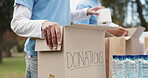 Volunteer, people and hands with donation box in park for social responsibility, outreach and charity. Packing, team and cardboard with food drive for community service, support and NGO project