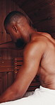 Black man, sauna and relax with towel for sweat, stress relief or hot steam at indoor salon. Young African or muscular male person in heat room for relaxation, detox or muscle and health treatment 