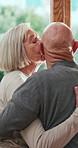 Senior couple, back or cheek with kiss by door in love, care or support together at retirement home. Elderly man, woman or hug in embrace, intimacy or romance by window for morning affection at house