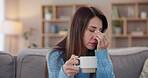 Woman, home and headache with coffee on sofa with stress, unhappy and pain in living room. Female person, couch and migraine in lounge with overthinking, burnout and tired or frustrated with tea