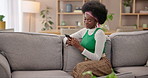 Home, typing and black woman on sofa, cellphone and social media with message, internet and smile. African person, apartment and girl with smartphone, texting and online chatting with mobile user