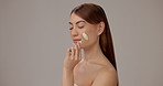 Jade roller, skincare and woman in studio for wellness, beauty and facial treatment for anti aging. Dermatology, salon and person with face tools for cosmetics, grooming and health on gray background