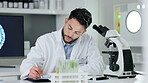 Healthcare analyst, medical technician and scientist working in a science lab. Handsome young man doing tests and experiments, recording his findings in a book and developing a cure or vaccination