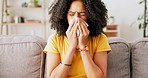 Sick, tissue and woman blowing her nose while sitting on a sofa in the living room of her house. African female sneezing while relaxing on a couch with a flu, cold or allergies in her modern home.