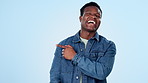 Smile, funny and pointing with a black man on a blue background in studio for an information announcement. Portrait, news and marketing for a young person laughing while showing space for advertising
