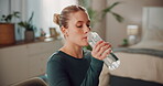 Woman, drinking water and home for fitness break, hydration and bottle of mineral liquid in bedroom. Female person, nutrition and thirsty girl for detox beverage, aqua and relax from yoga exercise