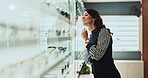 Happy woman, shelf and customer at optometry store for frame choice, vision correction or fashion lens. Client, smile and spectacles in optical shop for decision, eye care or check glasses for health