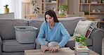 Laundry, happy and woman fold clothes with smile for housekeeping, spring cleaning and washing. Housewife, living room and task with basket of clothing, fresh linen or fabric organizing for home