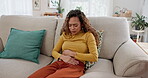 Woman, stress and stomach ache on sofa with PMS, period cramps and rubbing for relief. Menstruation, female person and hands on abdomen with constipation issue, gut health or anxiety in home for pain