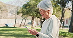 Cellphone, walking and senior woman in nature for exercise, activity and read online news. Smile, outdoor and elderly female person with workout for cardiac health in park, garden or field on phone.