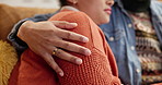 Hand, hug and couple on sofa in home with support, love and sympathy for mourning loss. Care, marriage and man embracing wife for connection with comfort, security or compassion in grief at house.