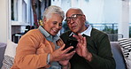 Elderly couple, phone and smile on sofa with media, photo memories and new memory aid app. Senior people, mobile and happy in home for innovative software, travel planning and choosing accommodation