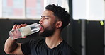 Man, thirsty and drinking water at gym, hydration and bottle of mineral liquid for nutrition. Male person, athlete and beverage for dehydration in workout, relax and aqua for fitness detox at club