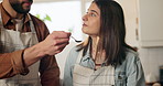 Couple, cooking and tasting food in kitchen for feedback, support and checking flavor. Home, meal and man feeding woman for skills, approval or relationship development in bonding activity for dinner