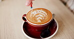 Coffee, cappuccino and hands with sugar in cafe for morning caffeine, breakfast or customer service. Cup, hot beverage and creative pattern in bistro for hospitality, espresso break or small business