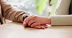 Holding hands, sympathy and senior couple by table for support, care or condolences for loss. Unity, home and elderly man and woman with connection for trust, commitment and love in marriage bonding.