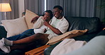 Home, funny and black couple on sofa, entertainment and watching tv in living room. African man, woman and laughing with comfort, joke or hobby with movie, humor and popcorn with fun and relationship