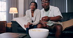 Home, eating and black couple with popcorn, entertainment and watching tv in living room. African man, woman and snack on sofa, comfortable and hobby with movie, marriage and series with relationship