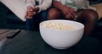 Couple, hand and popcorn for watching tv on sofa with movie, film or streaming show at home. Relax, television and people in living room with cinema snack, subscription service and weekend relaxing