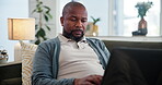 Black man, relax and typing on laptop at house for online report, freelancer and web design of project feedback. African, male person and digital for social media, research and reading blog in lounge