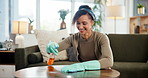 Woman, spray and cloth for table in home with gloves, smile and spring cleaning for hygiene in living room. Person, happy and bottle for liquid, disinfection and shine with ppe for bacteria in house