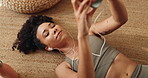 Cellphone, earphones and woman relax on floor in home listening to music with research for chakra. Calm, phone and female person streaming playlist with audio tech for mindfulness, peace and rest.