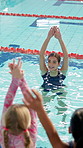 Woman, teacher and in swimming pool for lesson, stretching and happy with advice, development and learning. Person, coach and kids in water with warm up, exercise and training for wellness with sport