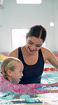 Teacher, woman and girl in pool for learning with smile, support and helping hand for swimming lesson. Person, coach and child in water with exercise for balance, stroke and development with safety