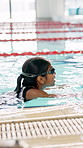 Girl, child and goggles in swimming pool for learning, stroke and profile with development, wellness or training. Kid, exercise and fitness at class with safety, progress and balance for water sports