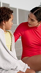 Pool, support and swimming coach with child in discussion for progress, development and help in lesson. Boy, towel and woman with conversation at aquatic center for sports, practice and guidance