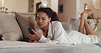 Woman, phone and lying on sofa in home, reading and texting with social media in living room. Girl, person and check smartphone on couch, notification and relax in lounge with mobile app at apartment