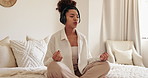 Woman, relax and meditation with headphones on bed for awareness, breathing and balance at home. Young, calm or female person with headset in lotus pose for audio therapy or peaceful music in bedroom