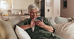 Senior woman, phone and happy on sofa, texting and reading with mobile app for contact in home. Person, smartphone and scroll with chat, notification and social network on lounge couch in retirement