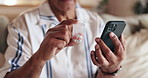 Senior man, hands or phone with pills for prescription, symptoms or telehealth on sofa at home. Closeup, elderly or male person with mobile smartphone or medication for side effect or dosage at house