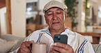 Coffee, happy and mature man with phone on sofa for social media, internet and online reading in home. Retirement, smile and senior person with mug for tea, warm beverage and drink in living room