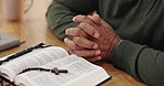 Bible, praying and hands of person in home for gospel lessons, learning and spiritual belief. Religion, Christianity and closeup of holy book for scripture, worship and reading for faith in God