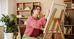 Creative, painting and woman with canvas in home with easel for artwork, drawing and illustration. Painter, artist and person with paintbrush for inspiration, expression and design in apartment