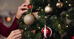 Hands, tree and ornaments for Christmas, celebration and holiday aesthetic in house with decoration. Woman, festive and vacation season in apartment for merry Xmas, party and event with sparkle ball